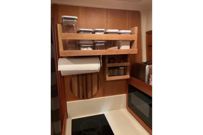 Yacht Photos Pics Compact kitchen storage in 2003 Mainship Pilot 34 boat, featuring wooden shelves and modern appliances.