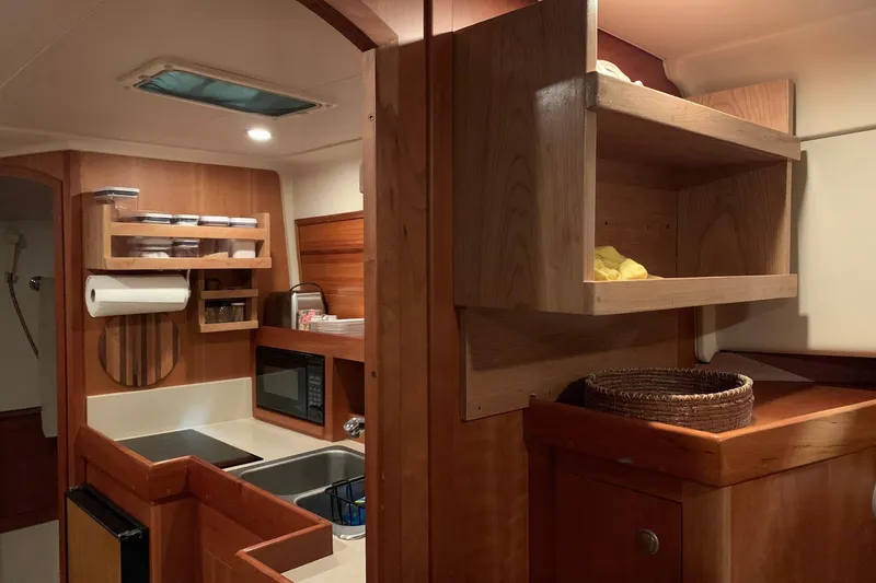  Yacht Photos Pics 2003 Mainship Pilot 34 galley with wooden cabinetry, microwave, and storage shelves.
