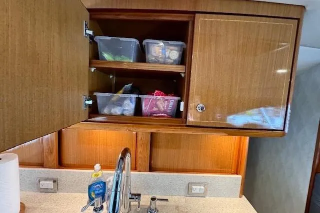 Pipe Dream Yacht Photos Pics Open wooden cabinet in 2005 Ocean Yachts 50 Super Sport kitchen, with organized storage containers.