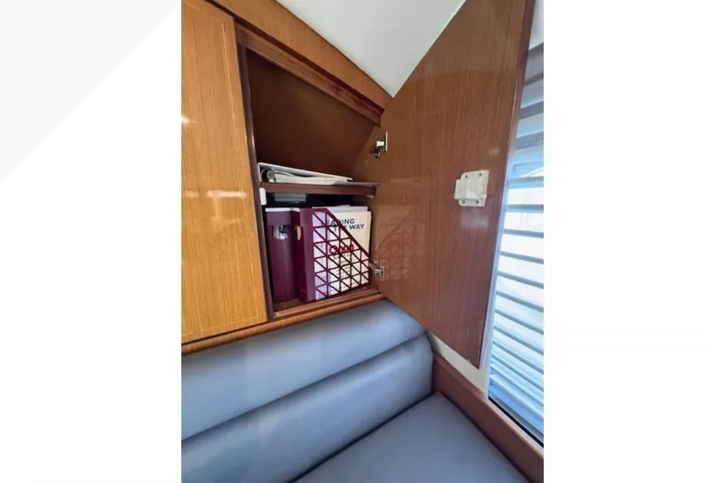 Pipe Dream Yacht Photos Pics Open wooden cabinet on 2005 Ocean Yachts 50 Super Sport, revealing storage items.