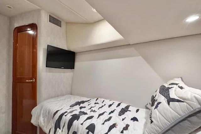 Pipe Dream Yacht Photos Pics 2005 Ocean Yachts 50 Super Sport cabin with bed, TV, and fish-patterned bedding.