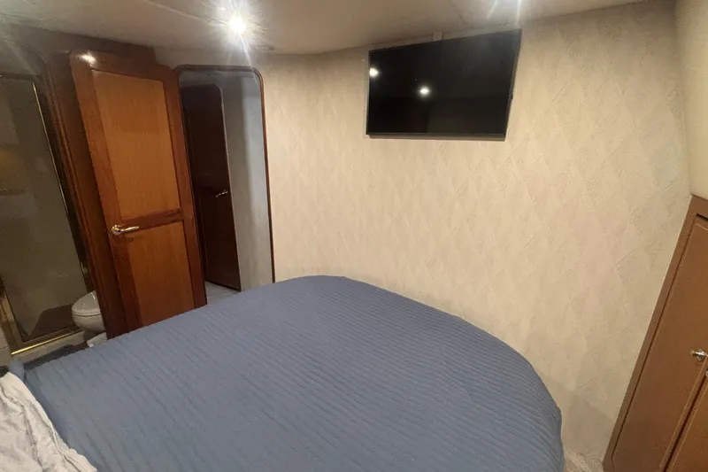 Pipe Dream Yacht Photos Pics Bedroom interior of 2005 Ocean Yachts 50 Super Sport with TV and wooden door.