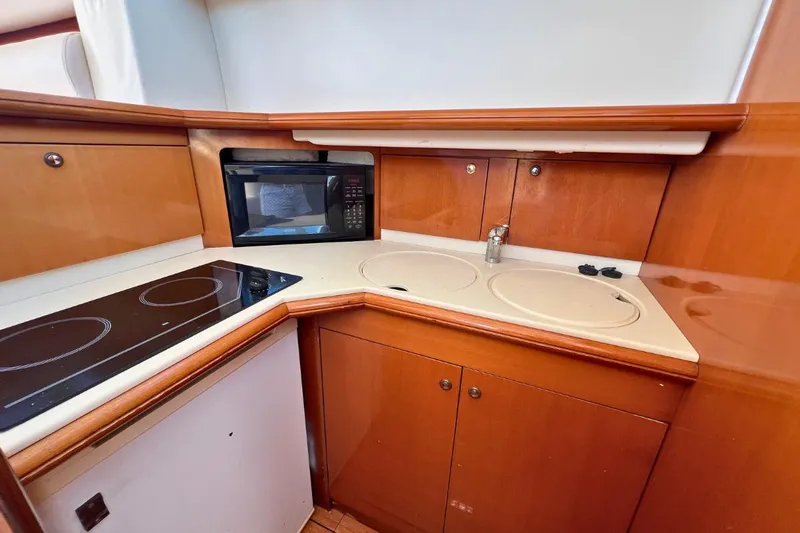  Yacht Photos Pics 2005 Jeanneau Prestige 36 yacht kitchen with stove, microwave, and wooden cabinetry.