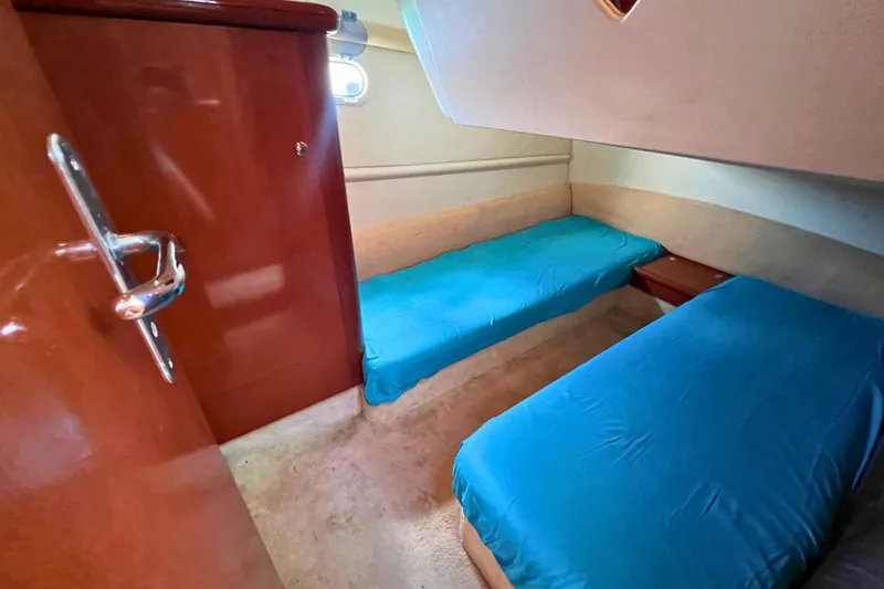  Yacht Photos Pics 2005 Jeanneau Prestige 36 cabin with twin blue-covered beds and wooden interior.