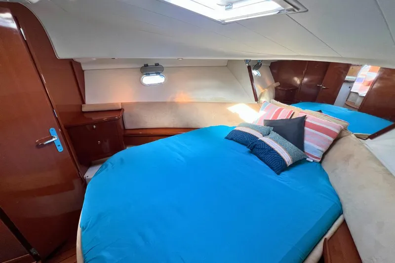  Yacht Photos Pics 2005 Jeanneau Prestige 36 cabin with blue bedding and wooden interior.