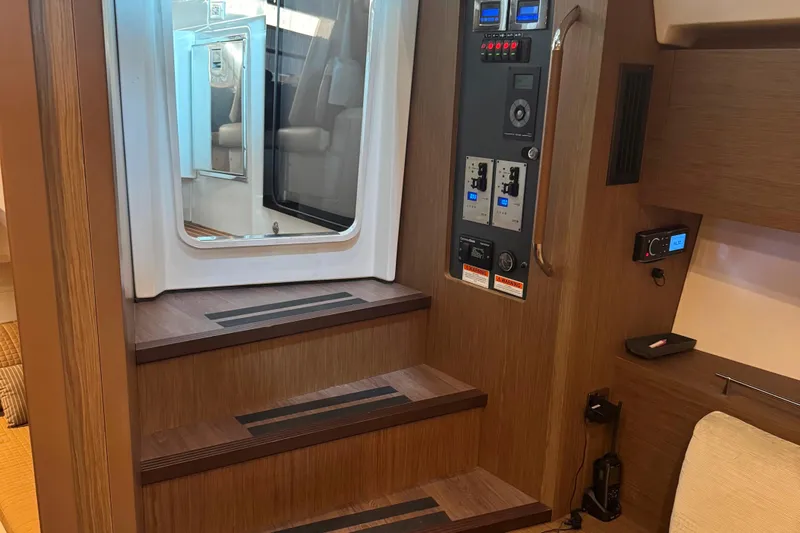  Yacht Photos Pics Interior of 2016 Beneteau Gran Turismo 40 yacht, featuring wooden stairs and control panel.