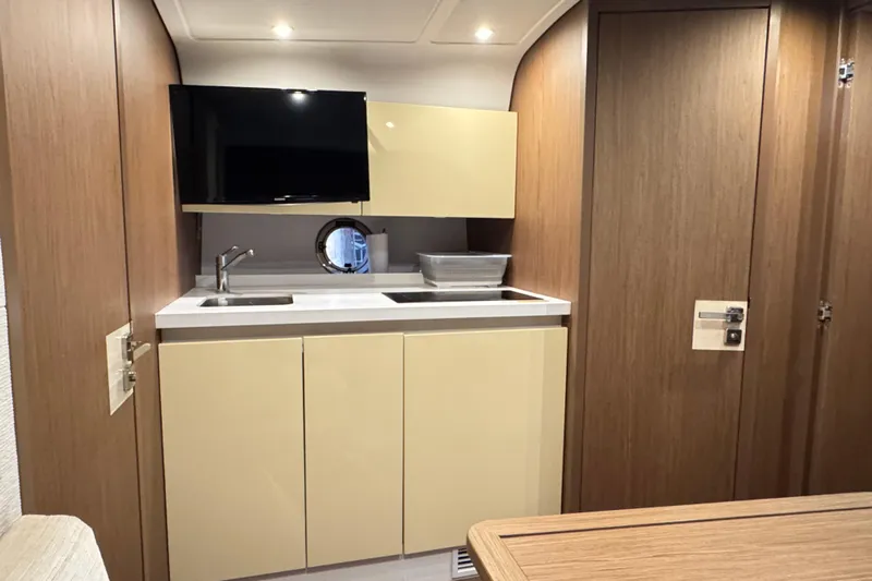  Yacht Photos Pics 2016 Beneteau Gran Turismo 40 yacht interior kitchen with modern cabinetry and porthole window.
