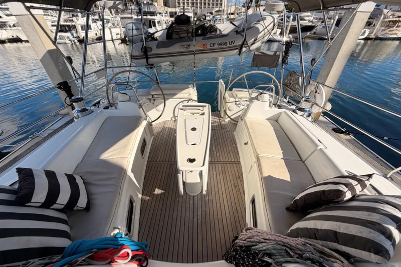 Set Free Yacht Photos Pics 2007 Beneteau 49 yacht cockpit with seating, striped cushions, and marina view.