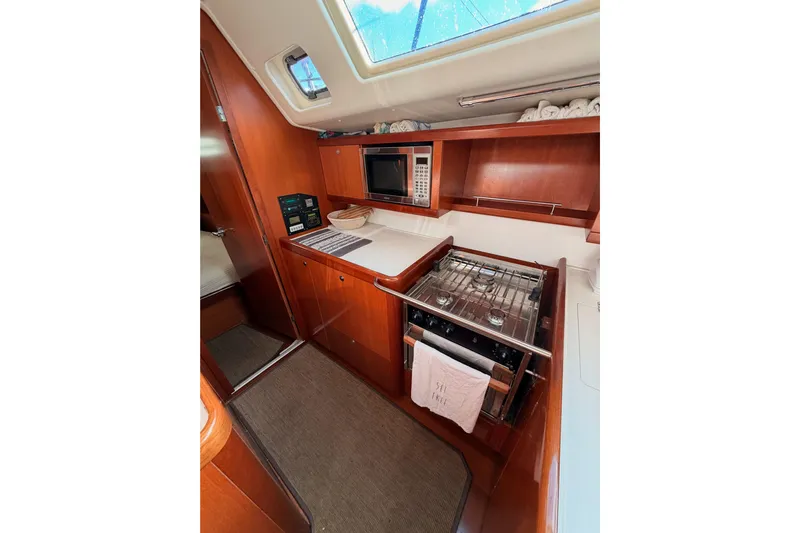 Set Free Yacht Photos Pics 2007 Beneteau 49 yacht kitchen with stove, microwave, and wooden cabinetry.