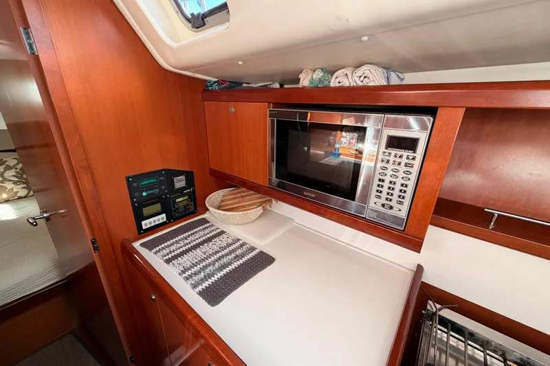 Set Free Yacht Photos Pics Interior of 2007 Beneteau 49 yacht with microwave and wooden cabinetry.