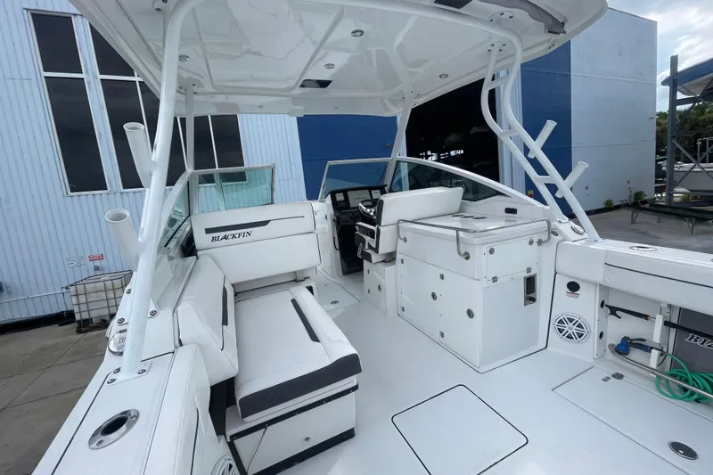  Yacht Photos Pics 2022 Blackfin 272 DC boat interior with seating and helm, docked near a building.