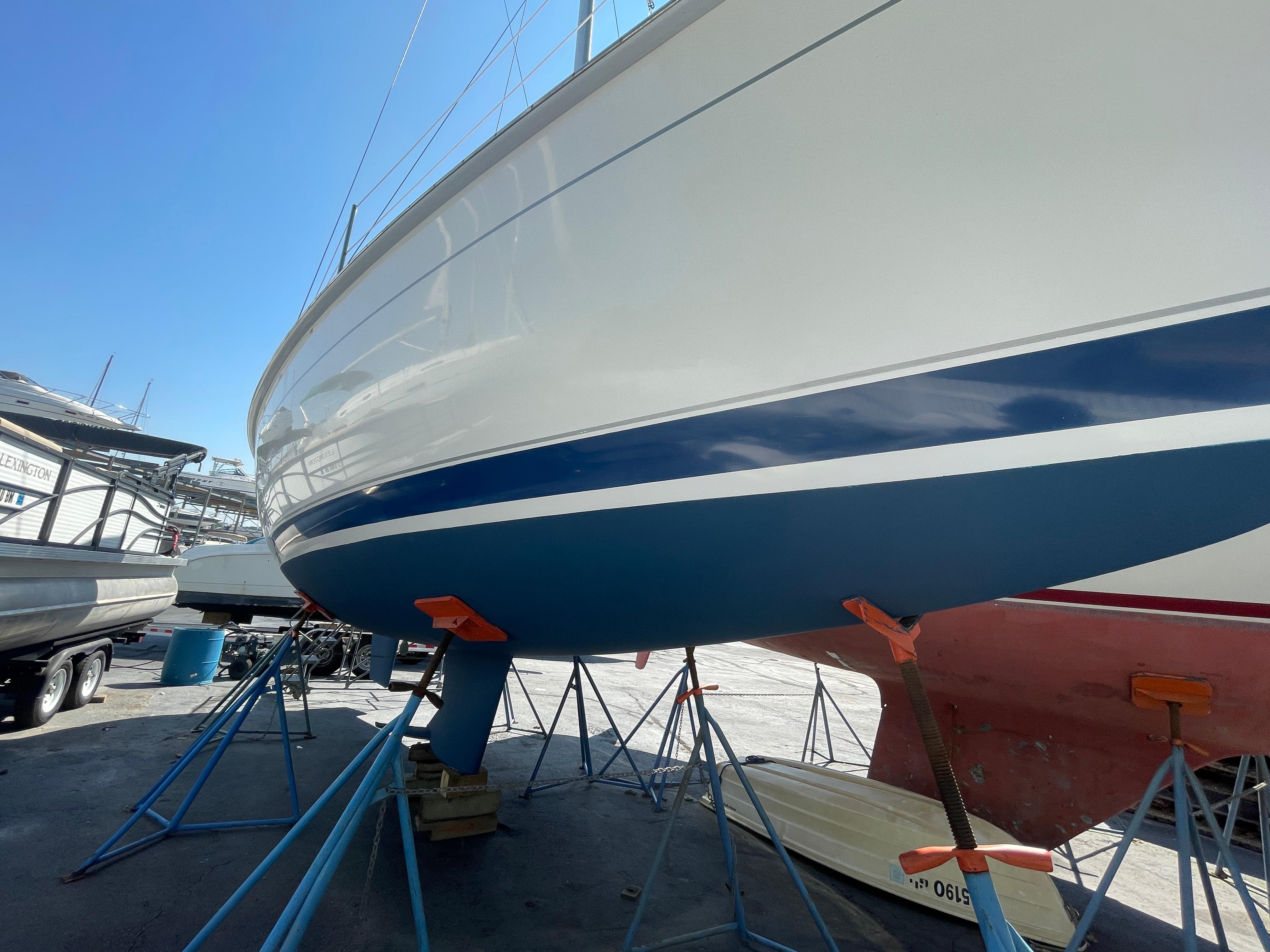 2001 Hunter 306 sailboat on stands in a boatyard under clear blue sky.