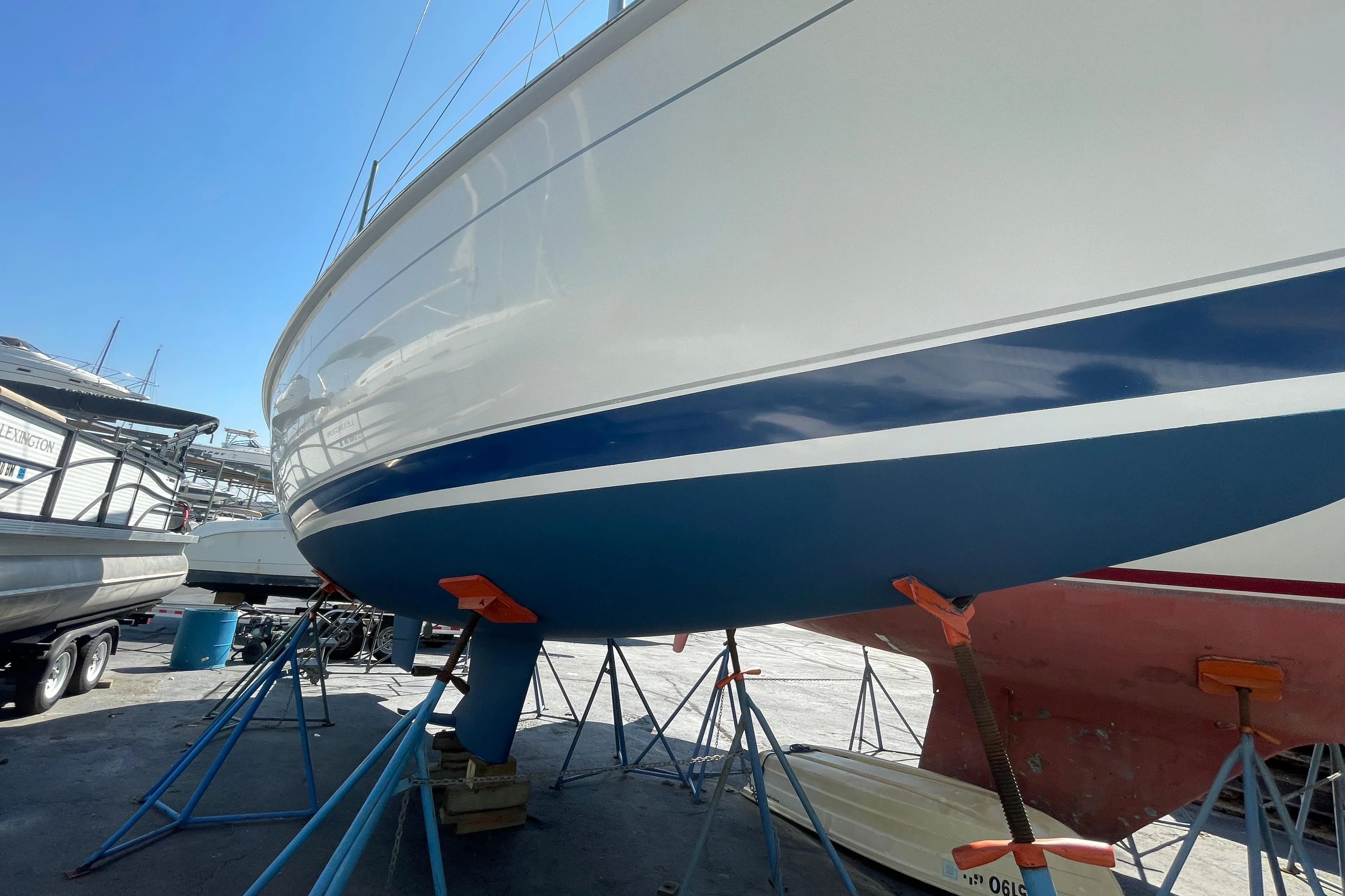 2001 Hunter 306 sailboat on stands in a boatyard under clear blue sky.