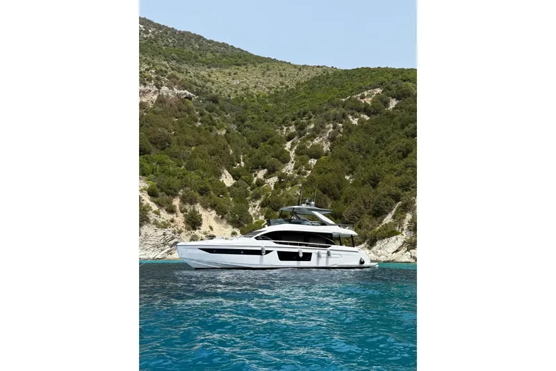  Yacht Photos Pics Azimut 68 FLY 2022 yacht cruising near a scenic, forested coastline.
