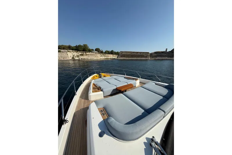  Yacht Photos Pics Azimut 68 FLY 2022 yacht with sun loungers on deck, cruising near rocky shoreline.