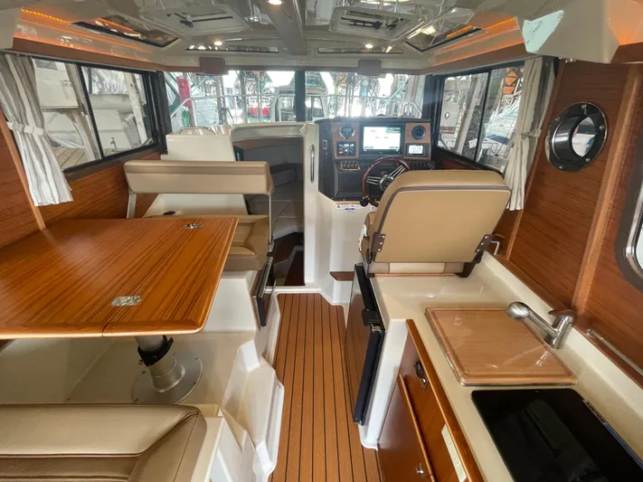 Beautiful Boat At Great Price! Yacht Photos Pics Interior of 2023 Ranger Tugs R-25 boat, featuring helm, seating, and kitchenette.