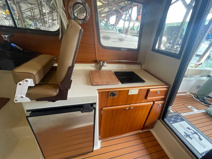 Beautiful Boat At Great Price! Yacht Photos Pics 2023 Ranger Tugs R-25 interior with kitchenette, featuring sink, fridge, and wooden cabinetry.