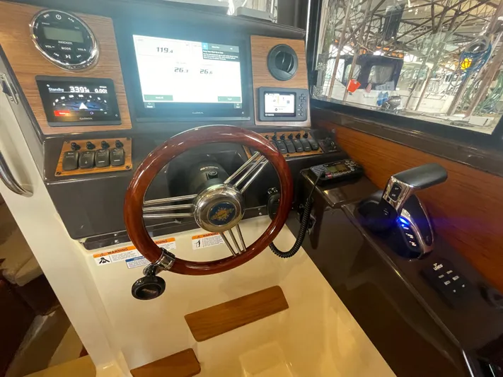 Beautiful Boat At Great Price! Yacht Photos Pics 2023 Ranger Tugs R-25 helm with wooden steering wheel and modern navigation controls.