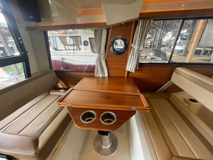 Beautiful Boat At Great Price! Yacht Photos Pics Interior of 2023 Ranger Tugs R-25 with wood table and beige seating.