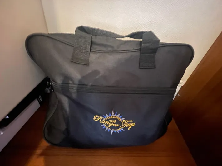 Beautiful Boat At Great Price! Yacht Photos Pics Black Ranger Tugs bag on wooden floor, featuring embroidered logo.