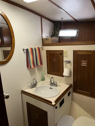 Shangri-la Yacht Photos Pics 1978 Cheoy Lee yacht bathroom with sink, mirror, and wooden cabinets.