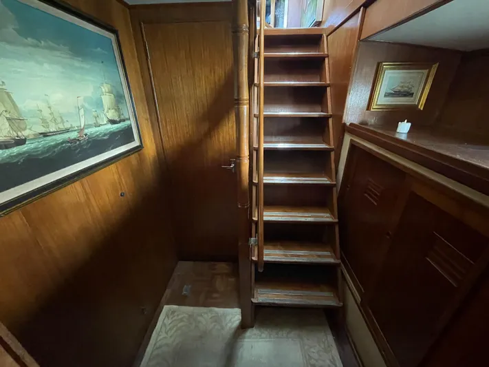 Shangri-la Yacht Photos Pics Interior of 1978 Cheoy Lee yacht with wooden stairs and nautical artwork.