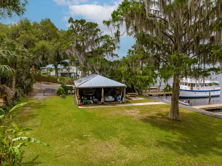 Shangri-la Yacht Photos Pics A 1978 Cheoy Lee boat docked near a lush, tree-lined waterfront with a small shed.