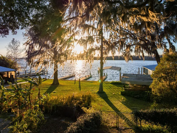 Shangri-la Yacht Photos Pics Scenic waterfront view with docks, lush greenery, and sunset through trees, Cheoy Lee 1978.