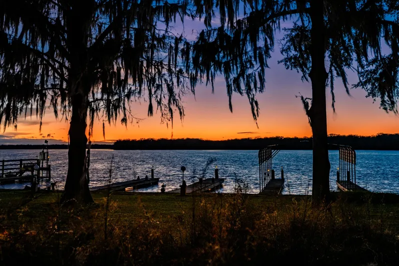 Shangri-la Yacht Photos Pics Sunset over serene lake with docks, framed by silhouetted trees, Cheoy Lee 1978.