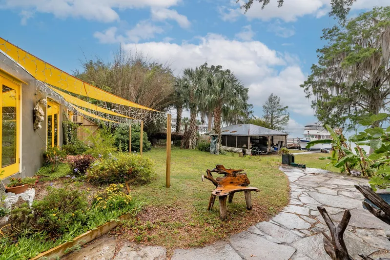 Shangri-la Yacht Photos Pics Sunny garden with stone path, yellow awning, and waterfront view, Cheoy Lee Ocean access deeded slips, 1978.