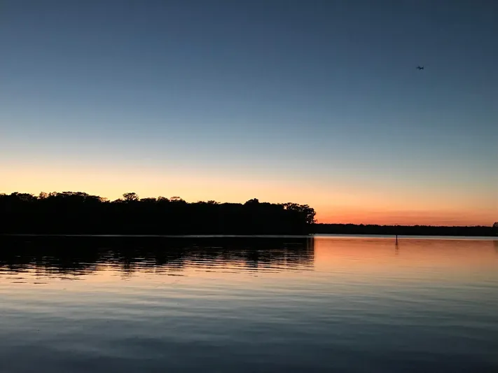 Shangri-la Yacht Photos Pics Sunset over calm water with silhouette of trees, Cheoy Lee Ocean access deeded slips, 1978.