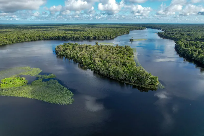 Shangri-la Yacht Photos Pics Aerial view of lush island surrounded by calm river under a cloudy sky.