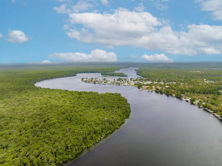 Shangri-la Yacht Photos Pics Aerial view of a serene river landscape with lush greenery and distant residential area.