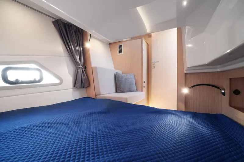  Yacht Photos Pics Interior of 2025 Skamander Monaco Coupe, featuring a cozy cabin with blue bedding.