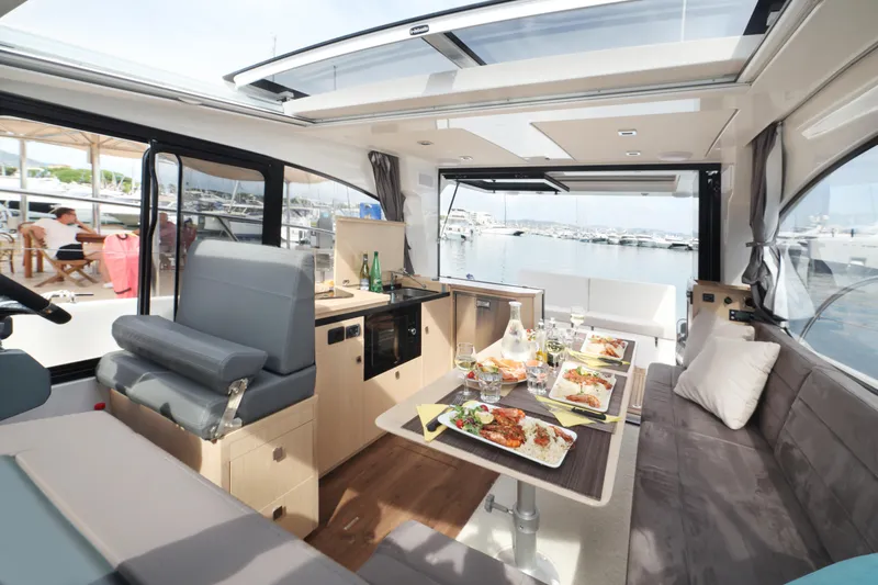  Yacht Photos Pics Luxurious interior of 2025 Skamander Monaco Coupe yacht with dining setup and marina view.