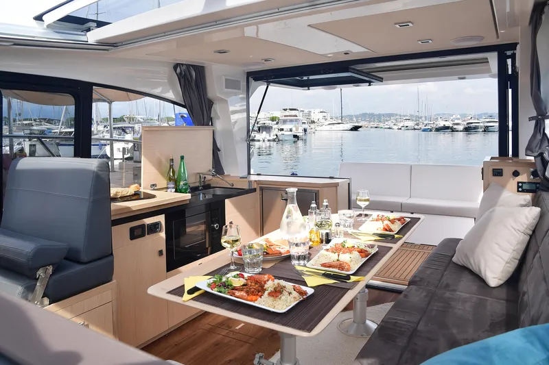  Yacht Photos Pics Luxurious interior of 2025 Skamander Monaco Coupe yacht with dining setup and marina view.