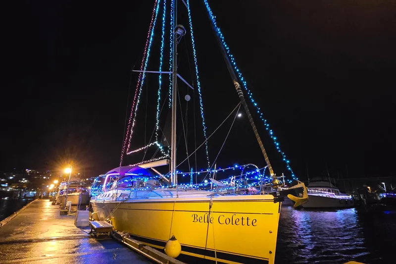  Yacht Photos Pics Yellow Hunter 49 sailboat, 2008 model, adorned with colorful lights at night dock.