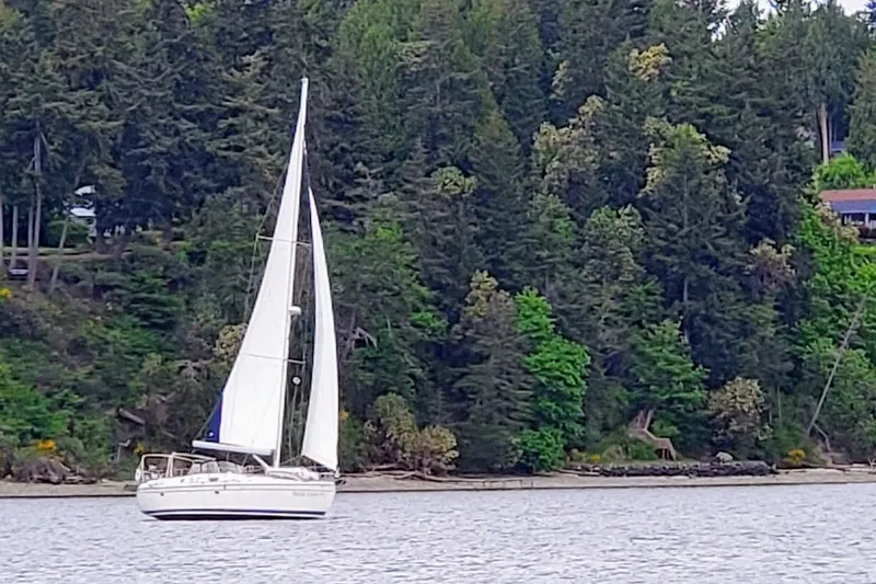  Yacht Photos Pics Sailboat Hunter 49 (2008) cruising near lush forested shoreline.