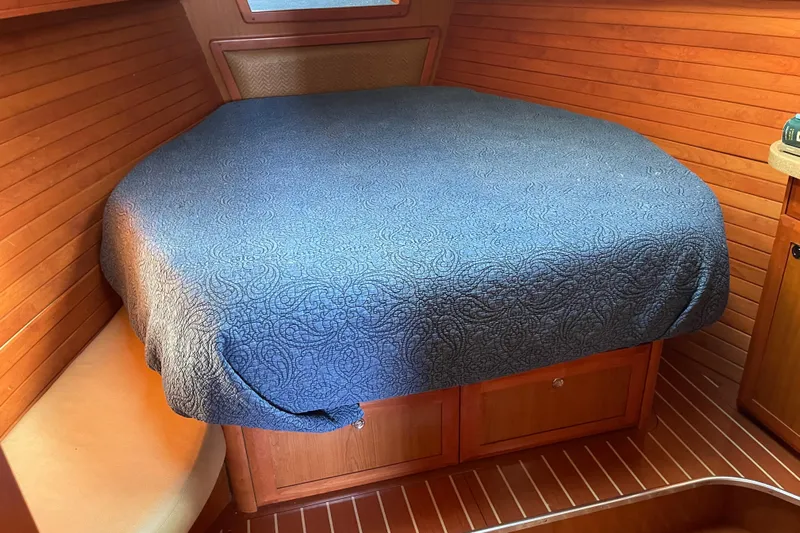  Yacht Photos Pics Cozy cabin interior of 2008 Hunter 49 yacht with blue bedspread and wooden paneling.