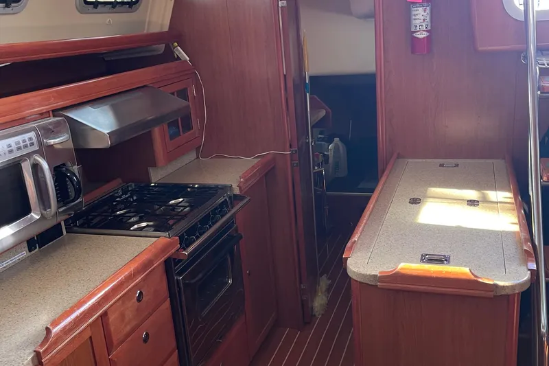  Yacht Photos Pics 2008 Hunter 49 yacht interior kitchen with stove, microwave, and wooden cabinetry.