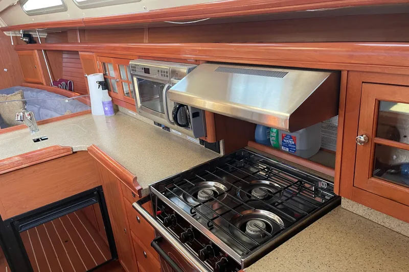  Yacht Photos Pics Galley kitchen in 2008 Hunter 49 yacht with stove, microwave, and wooden cabinetry.