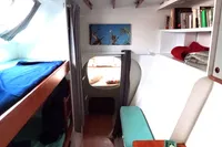 Interior of 1996 Custom Catamaran 60' with cozy cabin, bunk beds, and bookshelves.