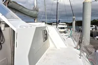 Custom 1996 CATAMARAN CUSTOM 60' docked, featuring sleek white design and netted railings.