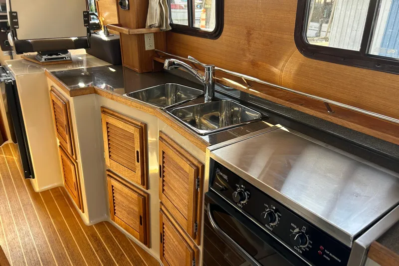  Yacht Photos Pics 2015 Ranger Tugs R-31 CB boat kitchen with wood cabinets, stainless steel sink, and stove.