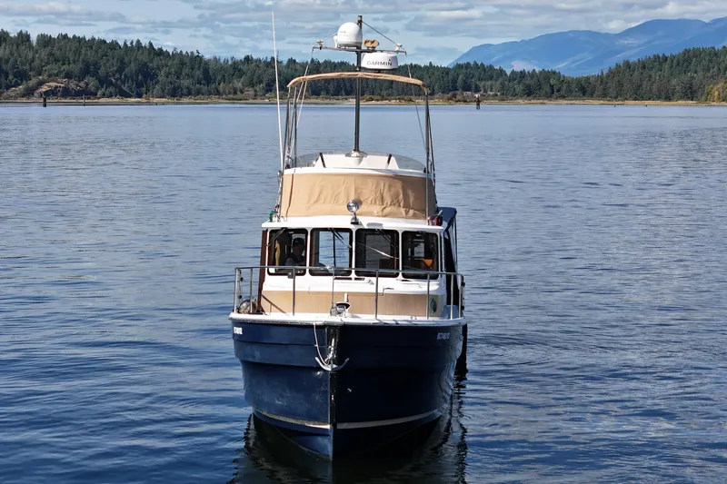  Yacht Photos Pics 2015 Ranger Tugs R-31 CB boat on calm water with forested shoreline and mountains.