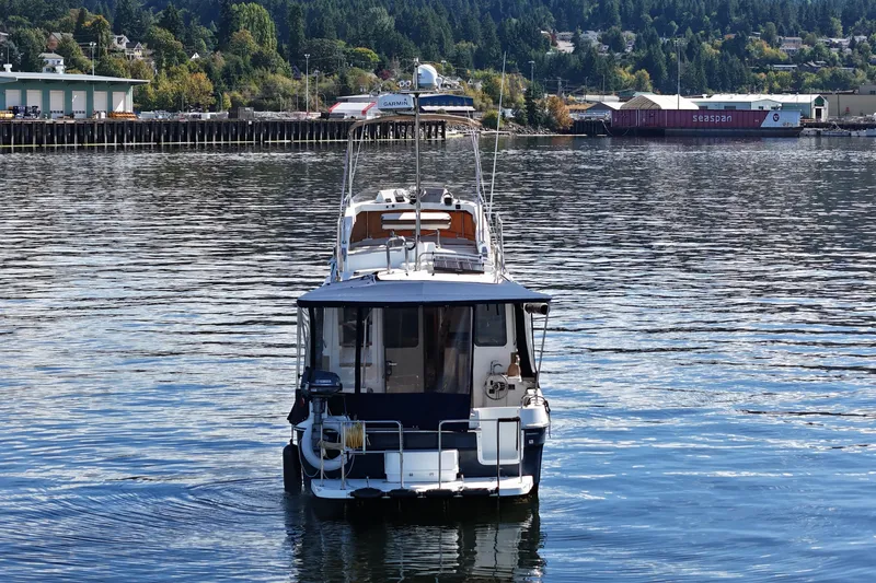  Yacht Photos Pics 2015 Ranger Tugs R-31 CB boat on calm water near a forested shoreline.