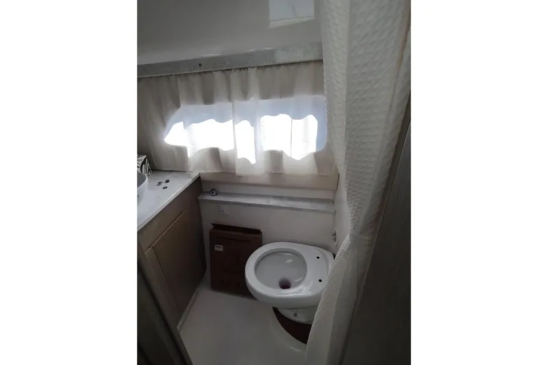 Me Yacht Photos Pics Bathroom interior of 2021 Regal 42 Fly yacht, featuring a toilet and window with curtains.