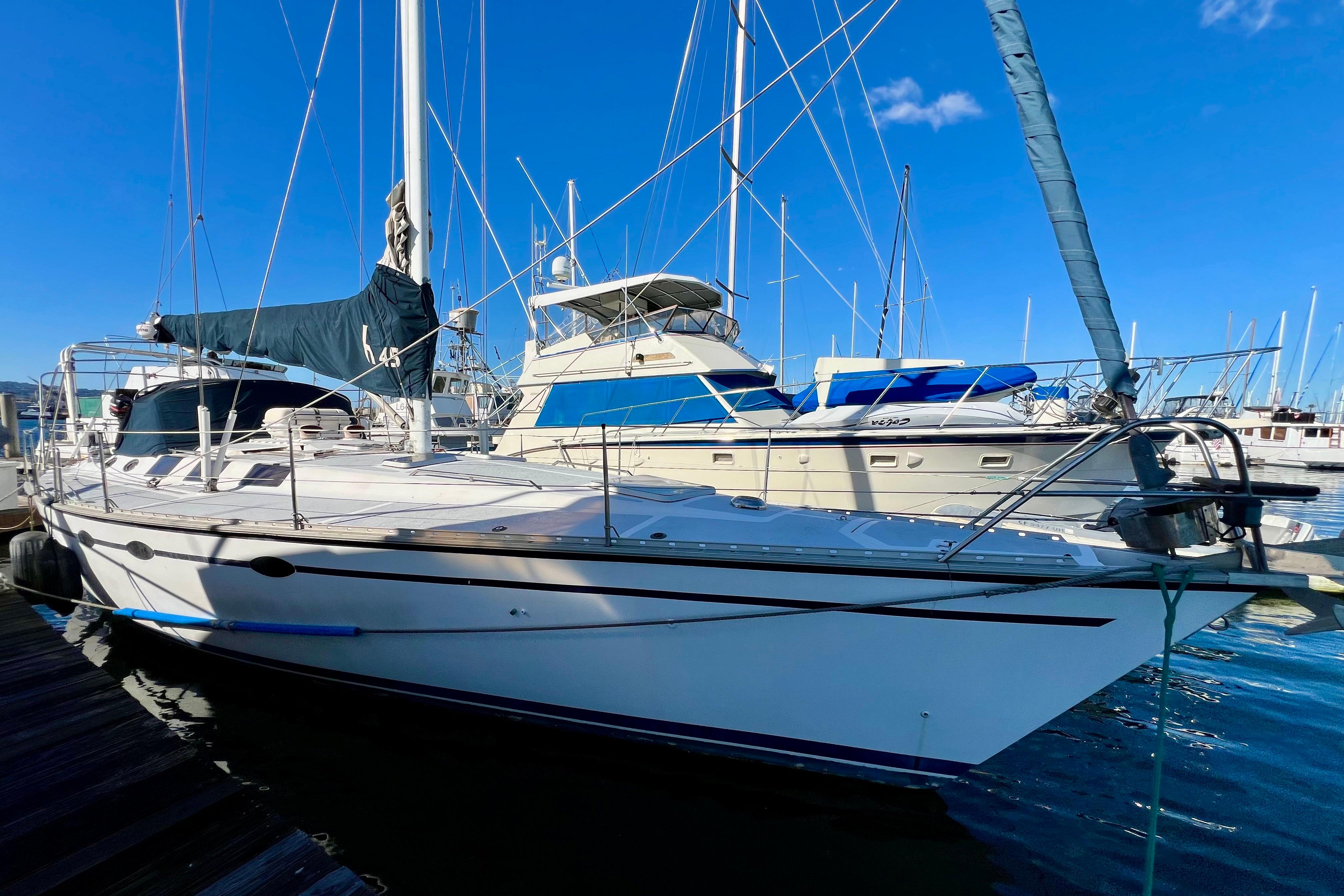 1986 Hunter Legend 45 sailboat docked at marina under clear blue sky.