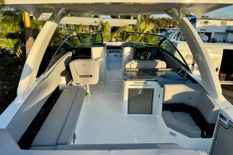  Yacht Photos Pics 2026 Four Winns H33 OB boat interior with modern seating and helm, surrounded by lush greenery.