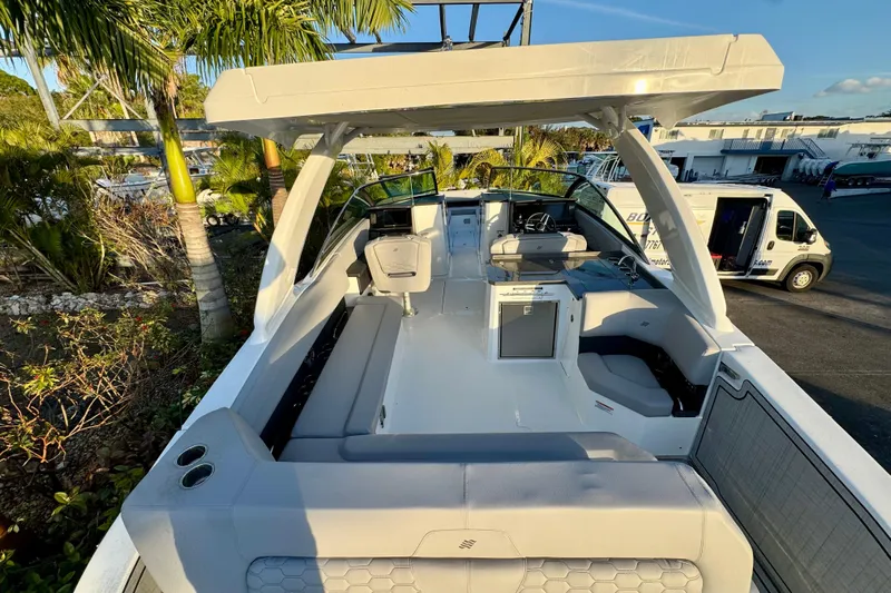  Yacht Photos Pics 2026 Four Winns H33 OB boat with spacious seating and modern design, docked near palm trees.